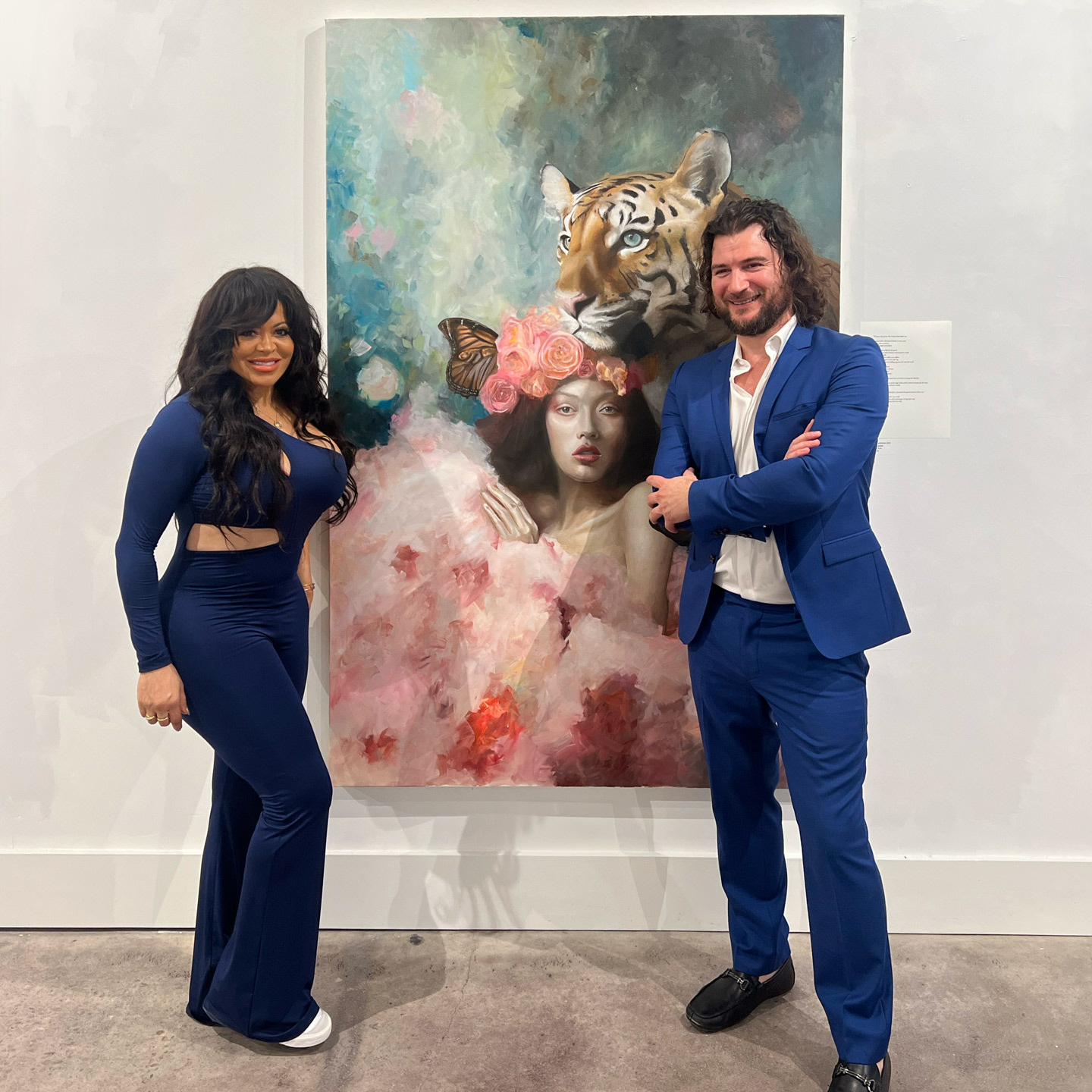 Alex e Stacy con "The Guardian" alla mostra d'arte 137 L'artista Alex Righetto in abito blu e Stacy in abito blu accanto al dipinto