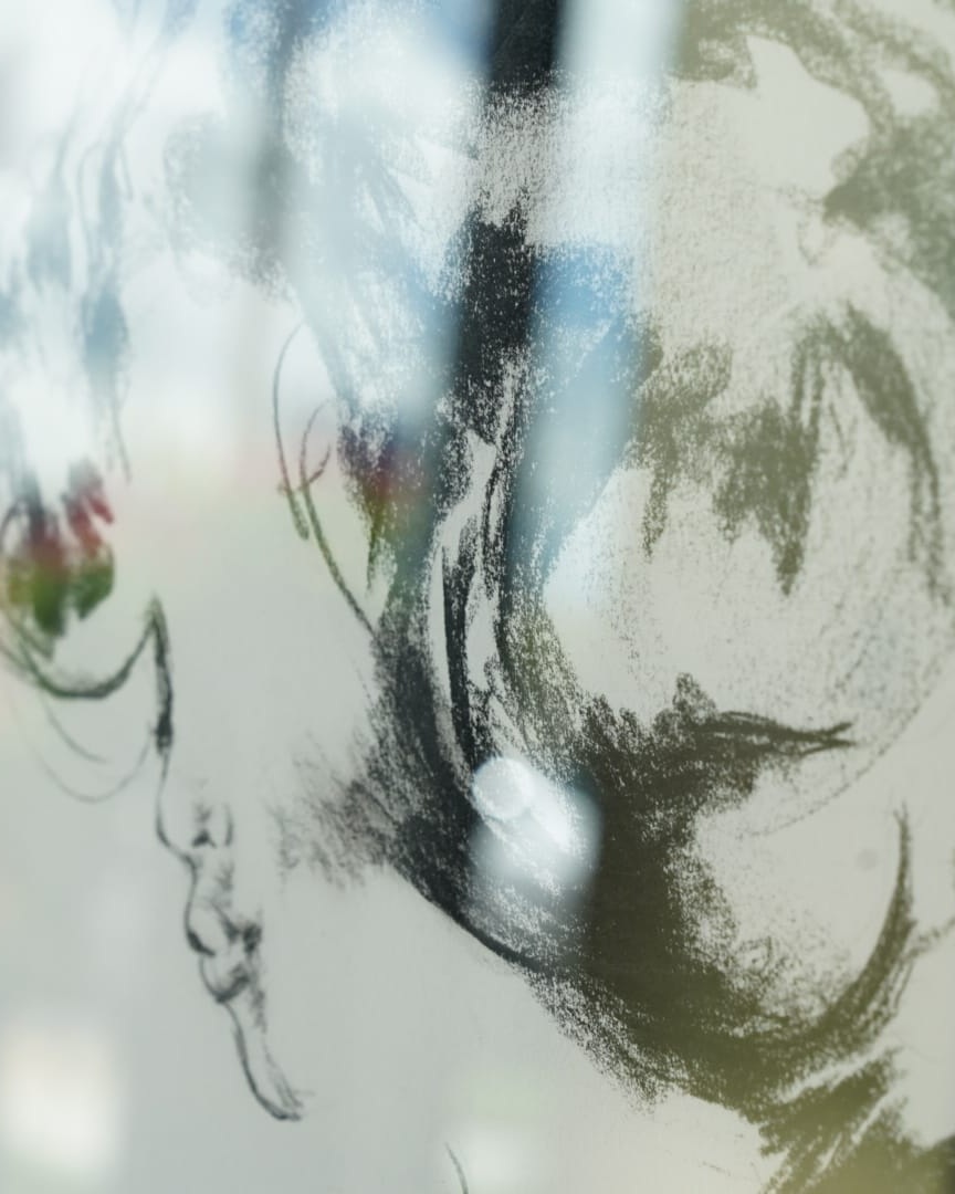 La Collezione Studio 7 Un disegno a matita dell'artista Alex Righetto, che raffigura un volto astratto con una miscela di linee sfumate e un tocco di colore, esposto su una superficie riflettente.