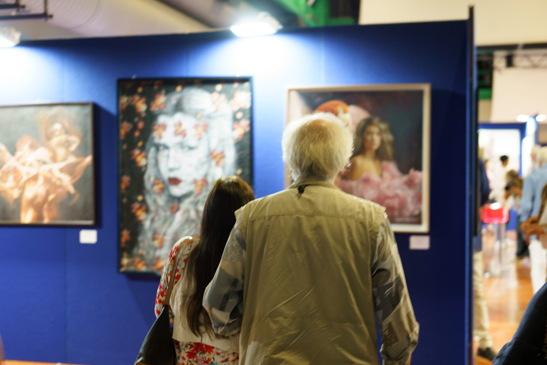 Alcune persone si avvicinano per vedere meglio il quadro di Alex alla mostra
