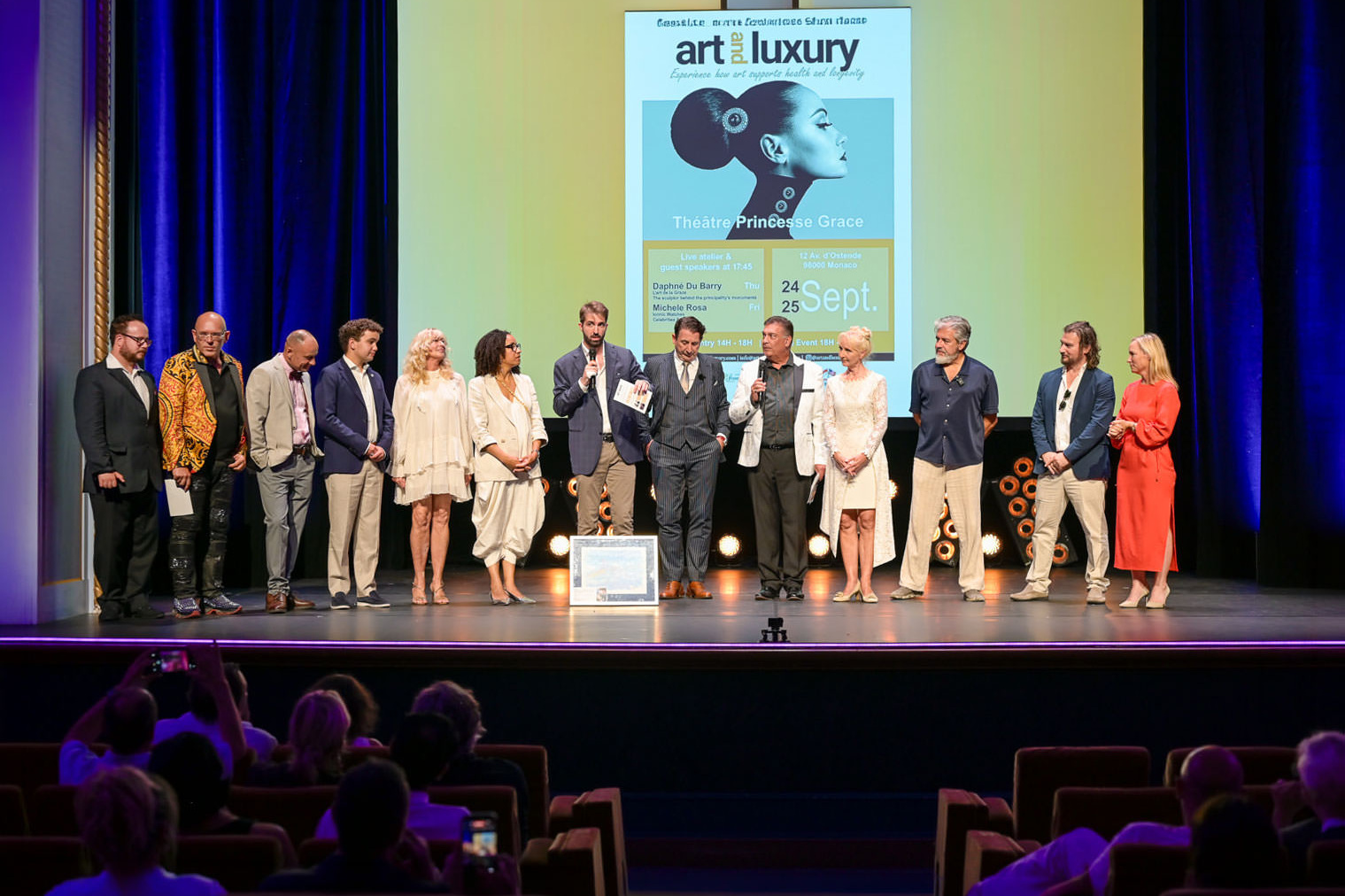 Alex Righetto sul palco dell’Art & Luxury Monaco 2026 insieme alla Principessa Margherita de Bourbon de Parme e all’organizzatrice dell’evento Annette, al Théâtre Princesse Grace.